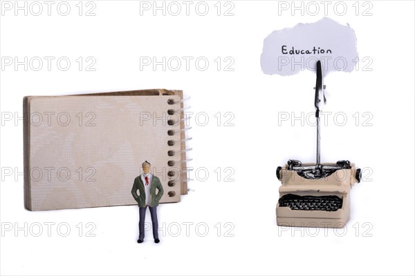 Man standing in front of a typewriter and a spiral notebook on a white background