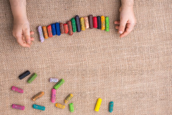 Toddlers hand putting crayons in line on canvas