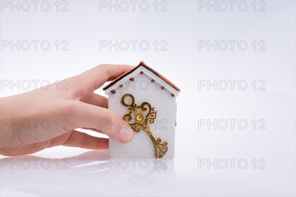 Hand holding a golden key near a house on a white background