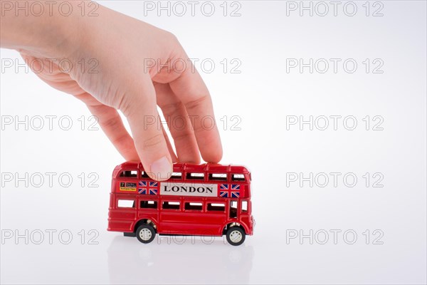 Child hand playing with London double decker bus model on white background