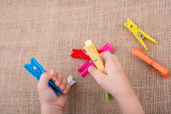 Color clothespin in hand on a linen canvas background