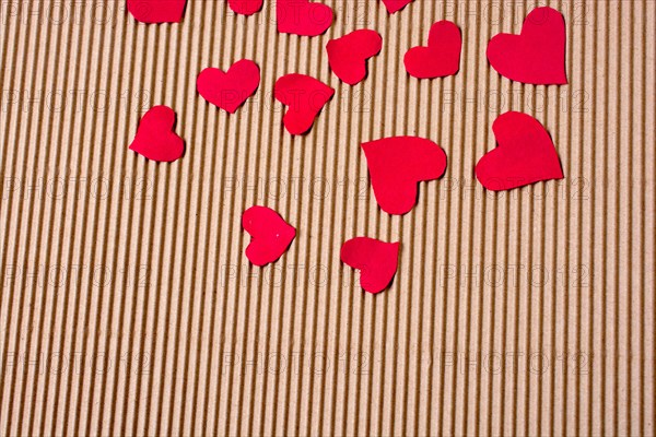 Red color paper hearts on a brown color cardboard