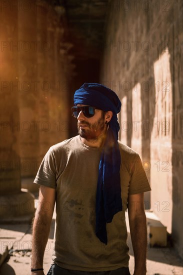 A young tourist in a blue turban visiting the Edfu Temple in the morning near Aswan city. Egypt