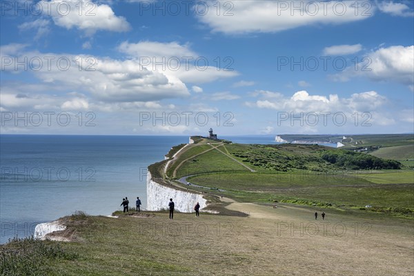 Tourists on the edge of the chalk cliffs at Beachy Head