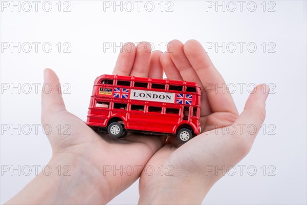 Hand holding a London double decker bus on a white background