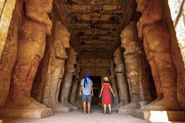 A tourist couple at the Abu Simbel Temple next to the sculptures