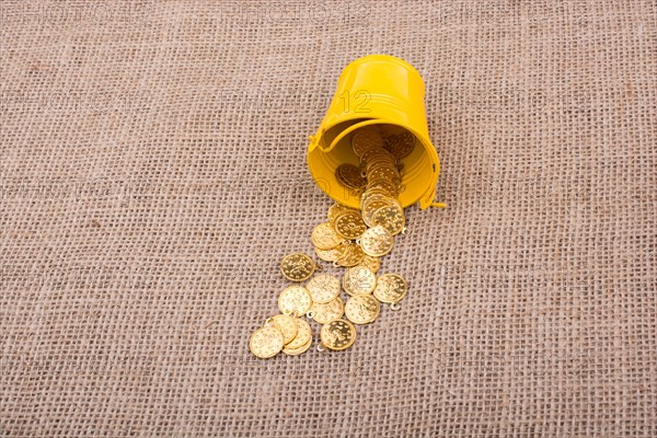 Bucket and plenty of fake gold coins on canvas