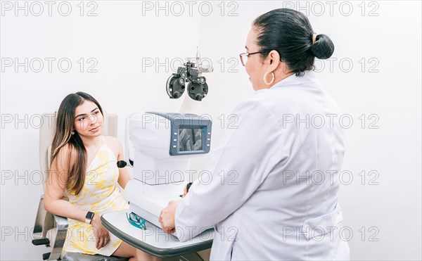 Optometrist with female patient in the autorefractor. Woman patient having consultation with optometrist in office