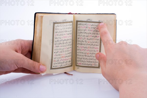 Hand holding The Holy Quran on a white background