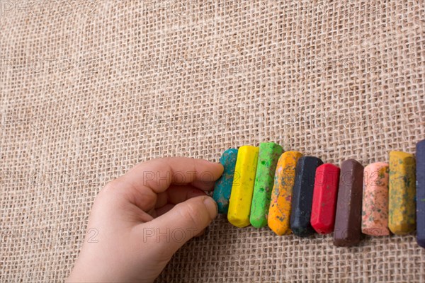 Toddlers hand putting crayons in line on canvas