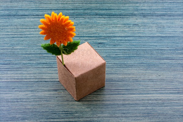 Fake orange color flower attached to a paper box cube