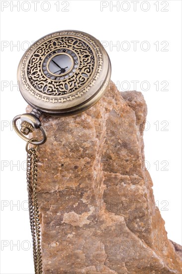 Pocket watch on the top of a rock on a white background