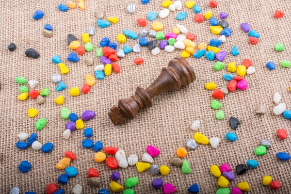 Chess king amid colorful pebbles on canvas background