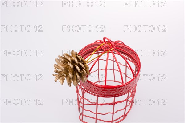 Pine cone in a red bird cage on a white background