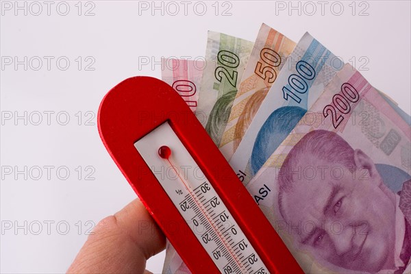 Turkish Lira banknotes by the side of a red color temperature on white background