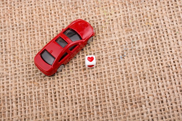 Love cube on a red toy car on a linen canvas