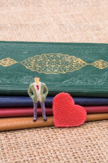 Man figurine beside a heart standing on little books
