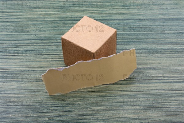 Torn paper and a paper box cube on wooden texture