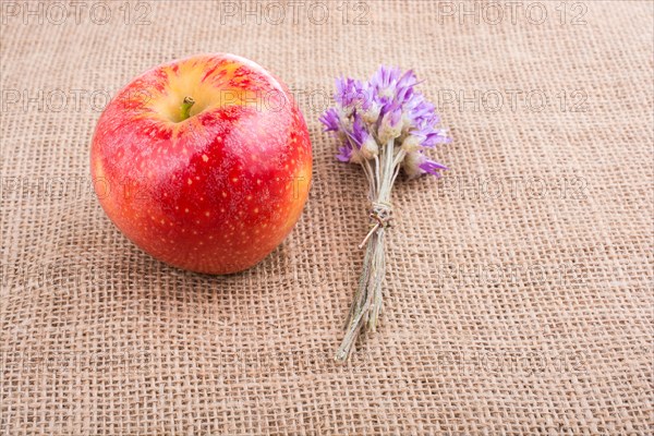 Tiny flower bouquet beside an apple on canvas