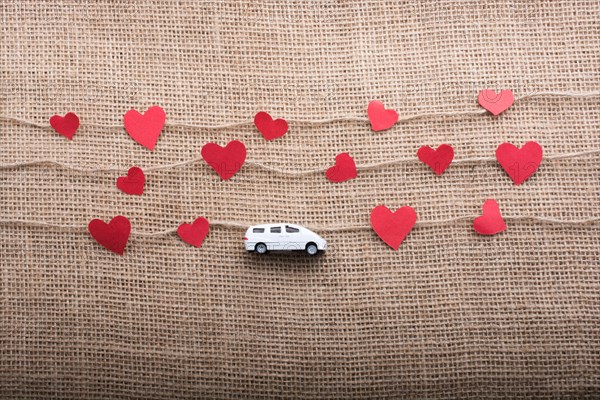 Love concept with car and paper heart on linen threads