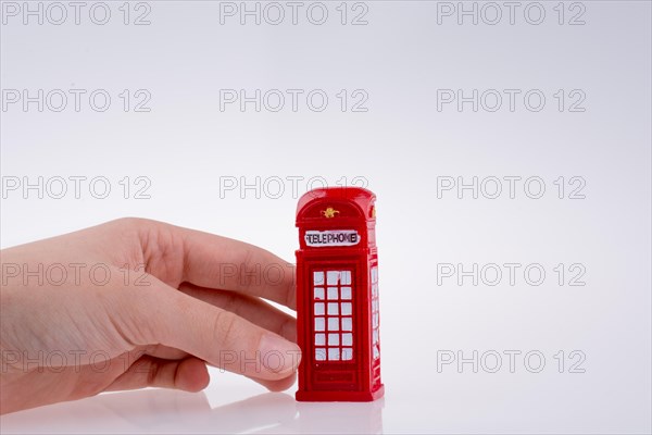 Hand holding a phone booth on a white background