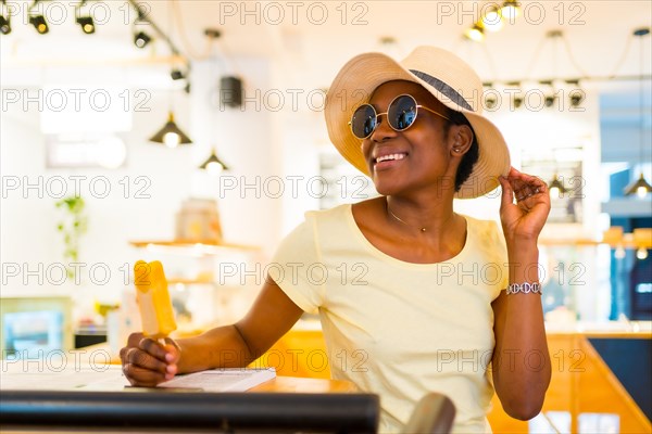 Portrait of African black ethnicity woman eating a mango ice cream in a shop