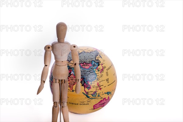 Wooden man standing in front of a globe on a white background