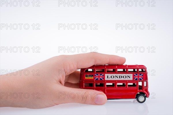 Child hand playing with London double decker bus model on white background