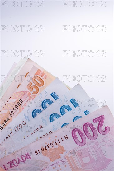 Turkish Lira banknotes by the side of a model house on white background