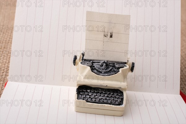 Retro syled tiny typewriter model on a paper background