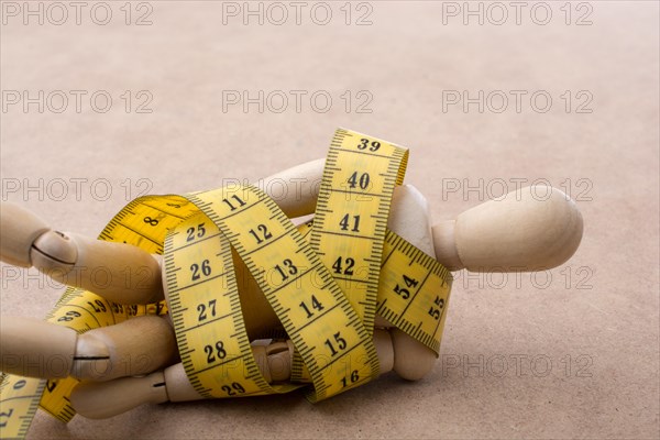 Yellow color measuring tape wrapped on wooden man