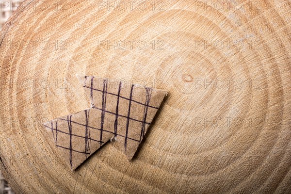 Arrow sign cut out of brown paper on piece of wood