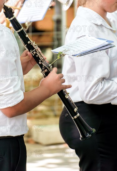 Woman's hands playing a clarinet with sheet music in the background