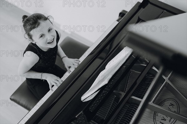 Elegant girl sits at the concert grand and plays the piano