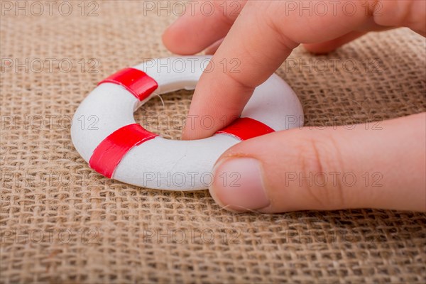 Hand holding a Lifesaver or life preserver on a fabric background