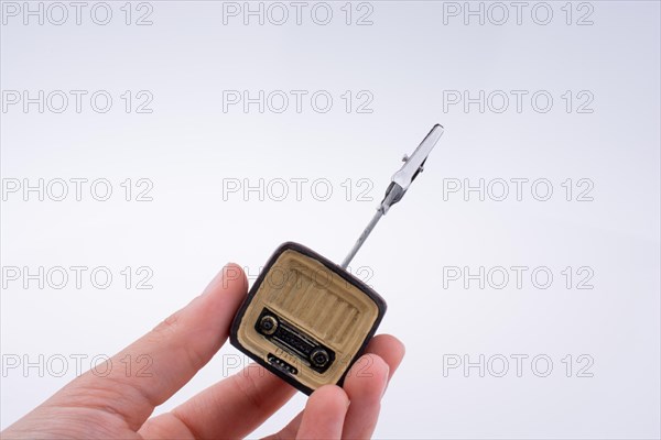 Hand holding a retro TV model on a white background