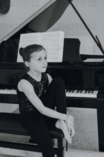 Elegant girl sits at the concert grand and plays the piano