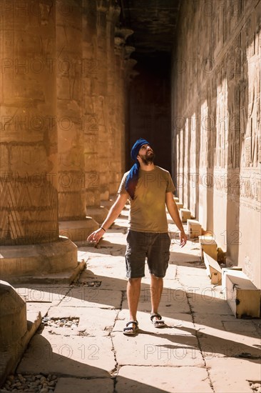 Young man in blue turban walking on the columns of the Edfu Temple near the city of Aswan. Egypt