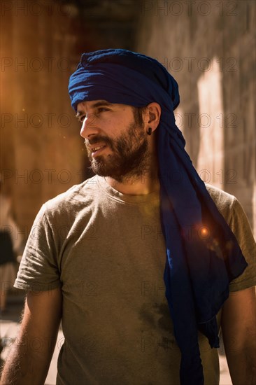 A young tourist in a blue turban visiting the Edfu Temple in the morning near Aswan city. Egypt