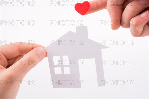 Paper house and heart shape in hand on a white background