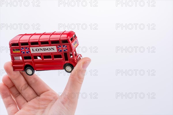 Hand holding a London double decker bus on a white background