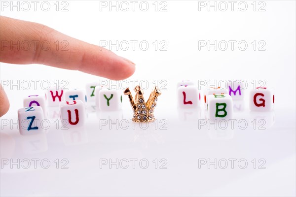 Hand pointing at Crown between Letter cubes on a white background