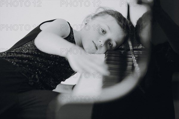 Elegant girl sits at the concert grand and plays the piano