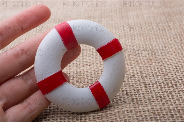 Hand holding a Lifesaver or life preserver on a fabric background