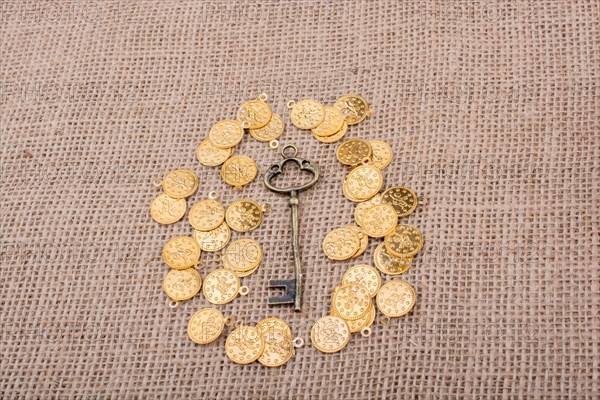 Hand holding a retro styled key over fake gold coins