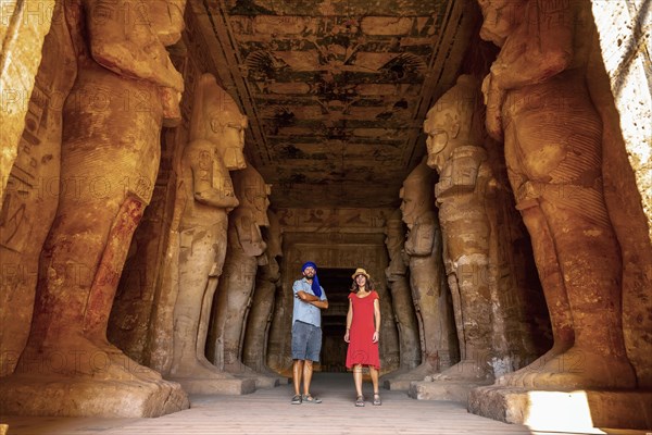 A tourist couple at the Abu Simbel Temple next to the sculptures