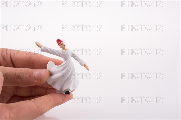 Hand holding a Sufi Dervis on a white background