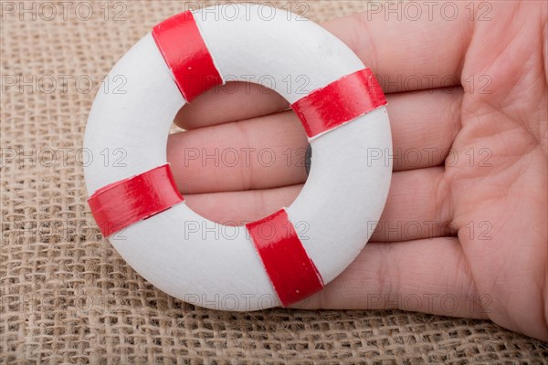 Hand holding a Lifesaver or life preserver on a fabric background