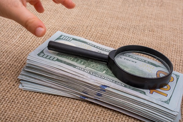 Toddler holding a magnifying glass over the banknote bundle of US dollar