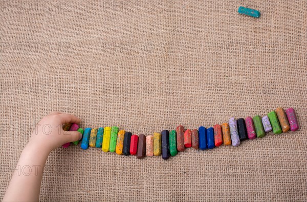 Toddlers hand putting crayons in line on canvas